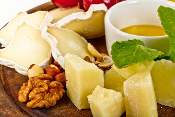 Various types of cheese with honey, nuts and grapes on plate, is