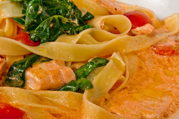tasty pasta with cream, salmon, cheese and parsley close up