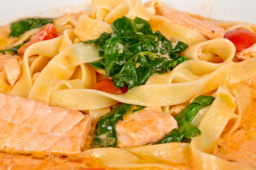 tasty pasta with cream, salmon, cheese and parsley close up