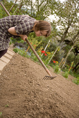 A girl with Down syndrome holding a garden rake.