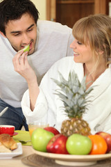 Young couple eating fruit at breakfast