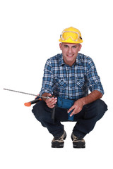 Man crouching with drill