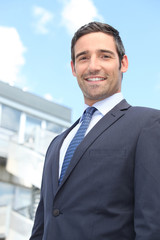 Young businessman in suit stood outside building