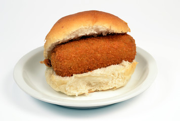 Roll with crispy calf croquette on a white context roll.