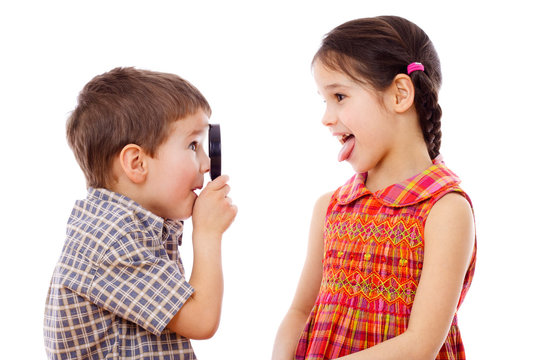Boy looks at girl with a magnifying glass