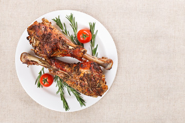 Roasted turkey legs on white plate with cherry tomato and rosema