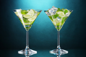 glasses of cocktails with lime and mint on blue background