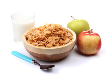 tasty cornflakes in wooden bowl, apples and glass of milk