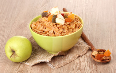 tasty cornflakes in bowl with dried fruits and apple