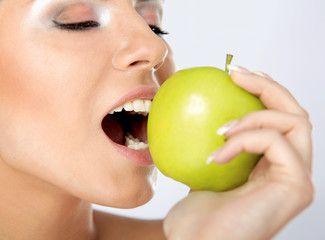 Young beautiful woman eating green apple