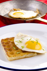 Potato waffle with fried egg on a plate