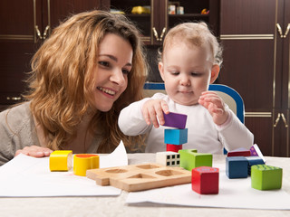 Mother and baby daughter building tower