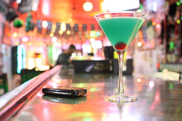 Blue Hawaiian cocktail and cellphone at a bar.