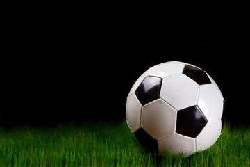 Fototapeta na wymiar Soccer ball on grass over black background