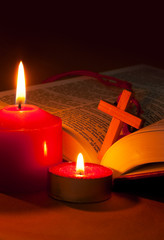 Open Bible with cross and burning candles