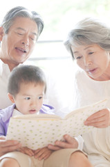 孫に絵本を読み聞かせる祖父母