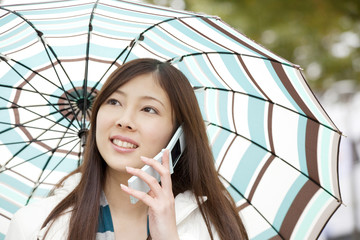 傘を差して携帯電話で通話する女性