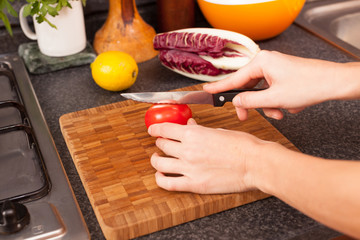 Woman Cutting Tomato in the Kitchen