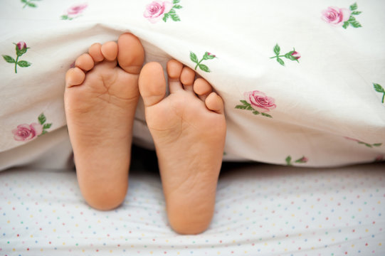 Young kid bare feet in bed.