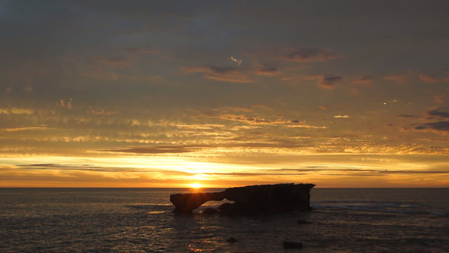 Ocean sunset with standalone rock