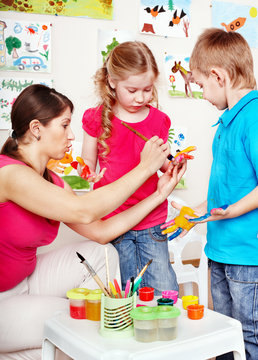 Children painting with teacher .