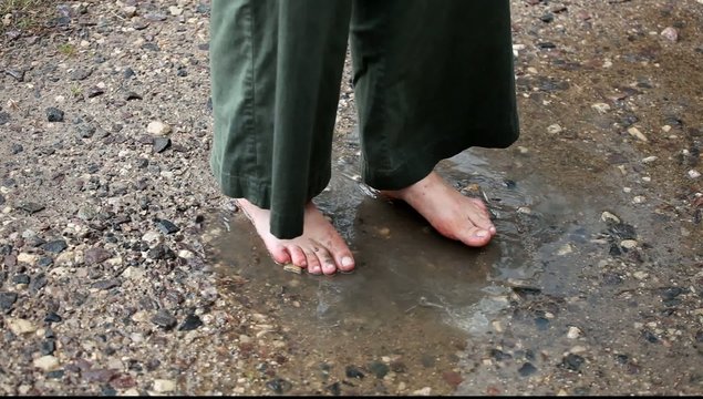Adult enjoying to splash barefooted in puddle
