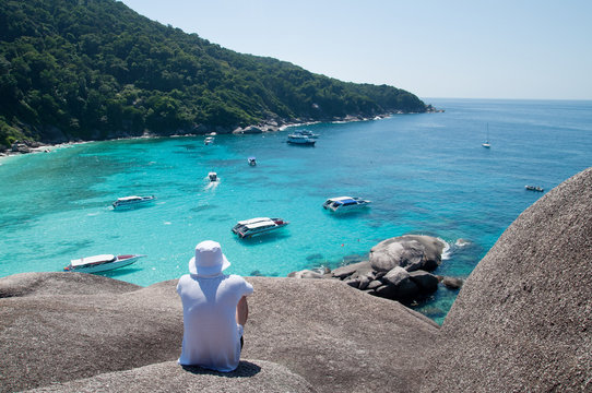 a man sitting on the big stone waching bay