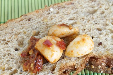 spicchi d'aglio sott'olio su fetta di pane ai cereali