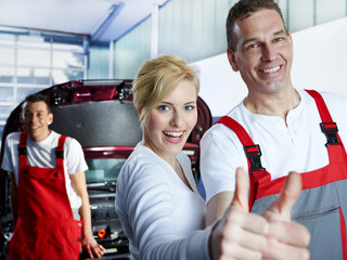 Motor mechanics and customer in garage show thumbs up