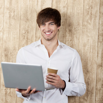 lachender junger mann mit laptop und kaffee