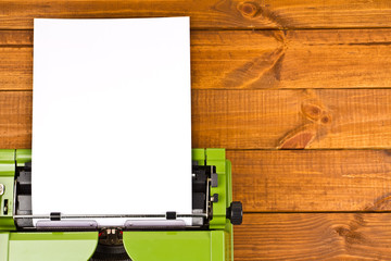 green typewriter on wooden ground with copyspace