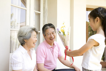 孫娘から花束をもらう祖父母