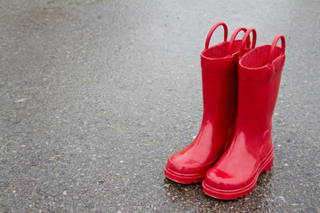 Red rain boots on wet pavement