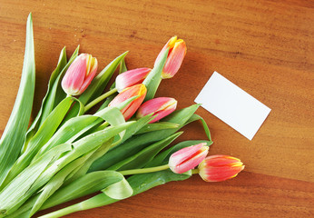 Bouquet of tulips on the table and empty white card