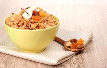 tasty cornflakes in bowl with dried fruits on wooden table