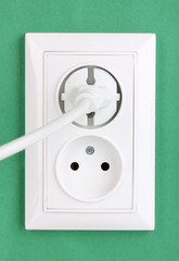 White electric socket with plug on the wall