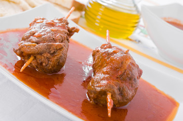 Meat roulade on white dish.