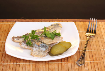 Tasty mackerel on plate on wooden mat on brown background