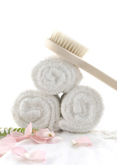 Natural wooden brush on roller towel with flower petals