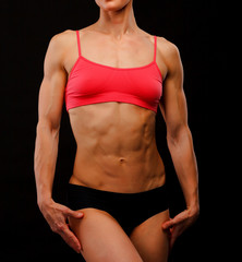 Fototapeta na wymiar Muscular female body against black background.