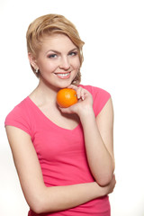 Smiling girl with orange in pink dress isolated on white