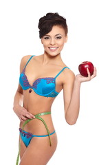 smiling brunette woman in blue lingerie with red apple measuring