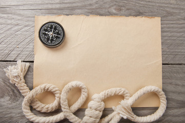 old compass, rope and an old paper on wooden background