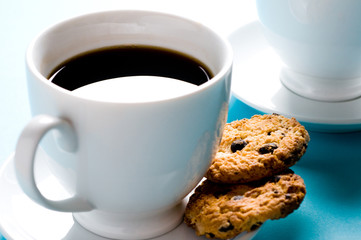 Two coffee cups with cookies on blue background