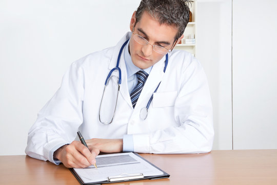 Male Doctor Writing on Clipboard