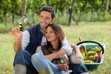 Couple enjoying a bottle of wine whilst harvesting grapes