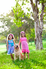 Obraz premium Two happy little girls and a golden retriever