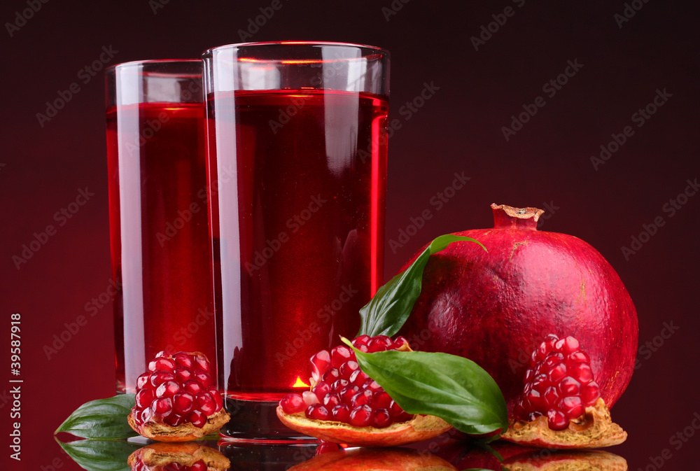 Sticker ripe pomergranate and glasses of juice on red background