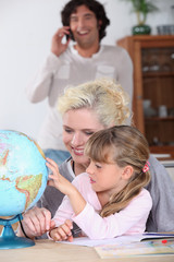 Woman helping her daughter complete her  geography homework