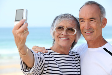 Older couple taking their own photograph at the beach